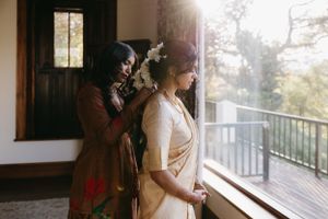 Getting ready moment in sunlit room with wedding dress preparation.