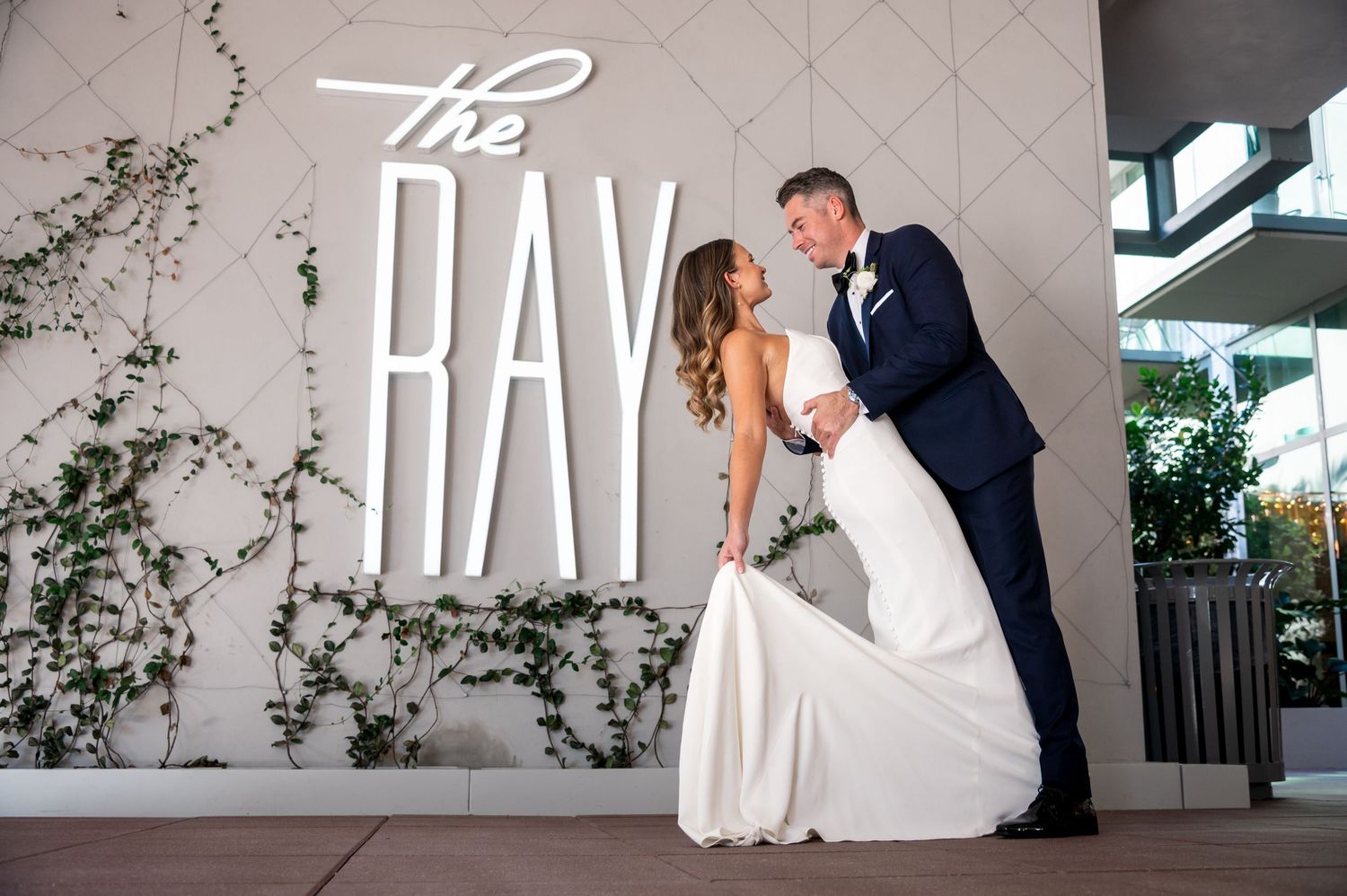 The groom dips his bride in front of The Ray Hotel, photographed by Palm Beach wedding photographers, Our Story Imagery.