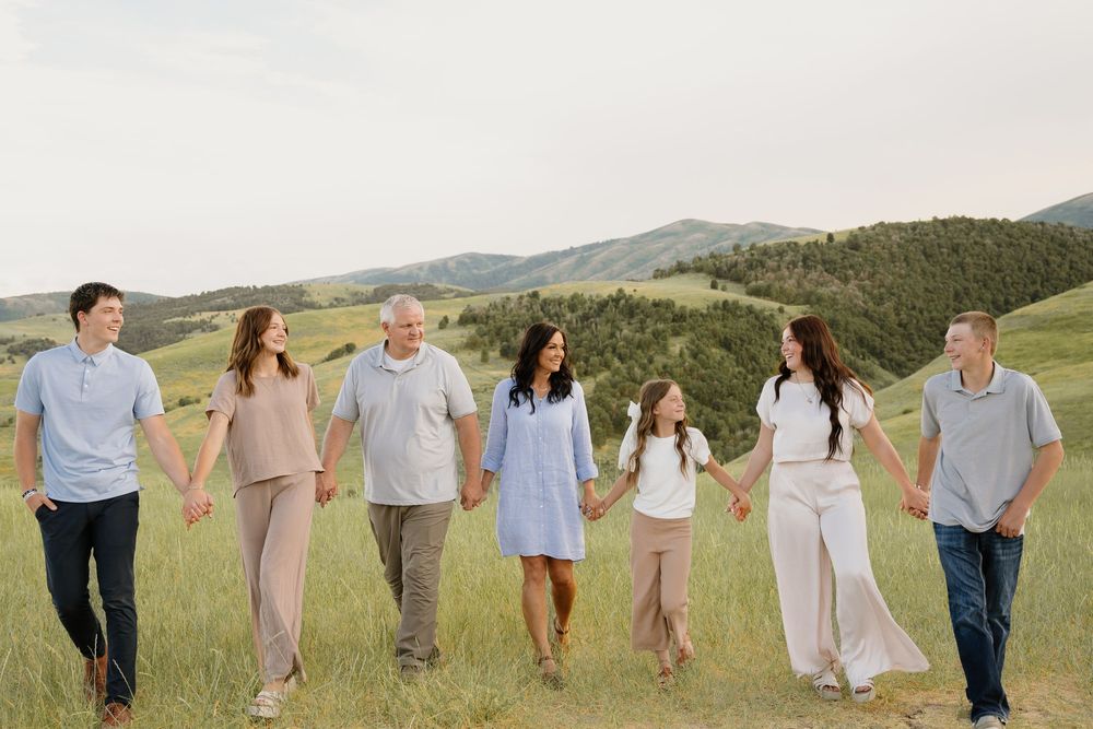Group enjoying a relaxed walk together in casual attire across rolling hills and grassy meadows on a sunny day.