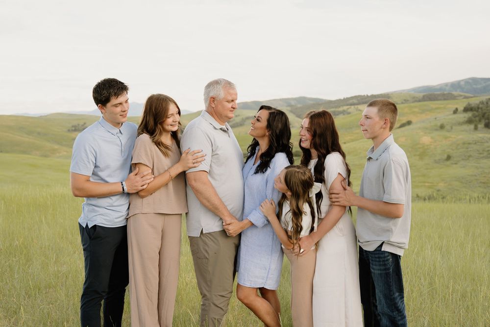 Group sharing candid moments and laughter together in a scenic mountain meadow setting at golden hour.