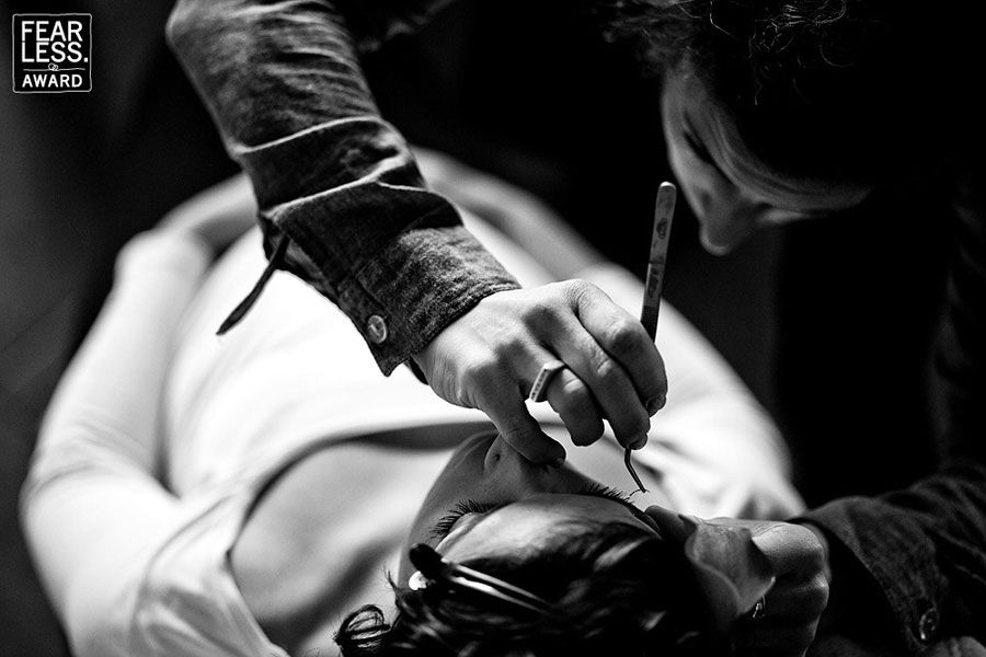 Professional tattoo artist at work shown in black and white photograph, using a tattoo machine on client.