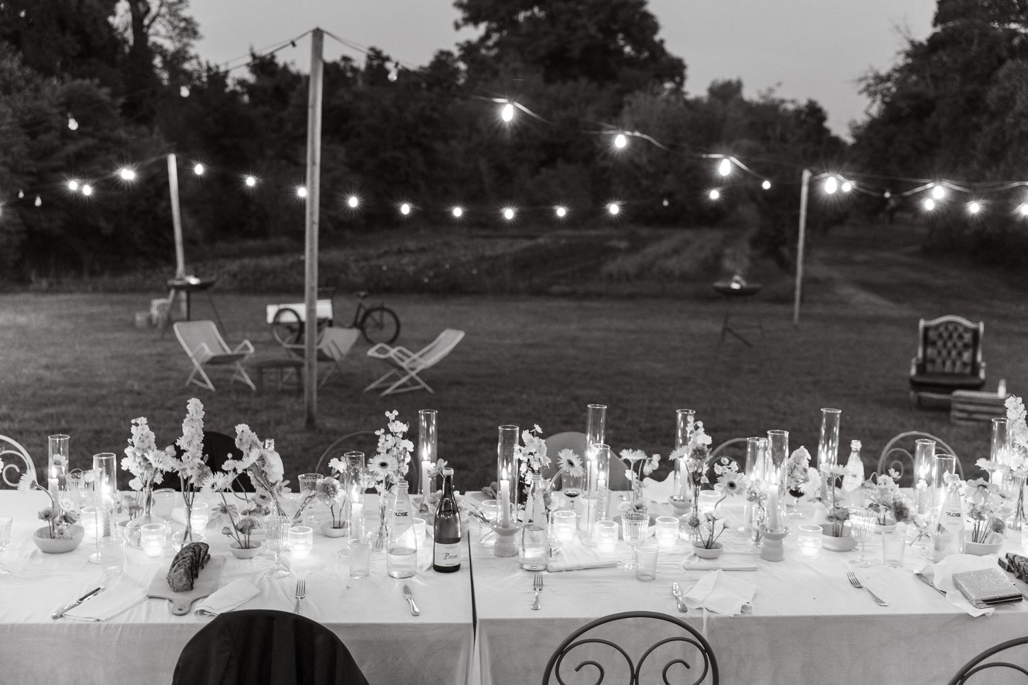 Elegant outdoor dining table setup with string lights overhead at dusk creating a romantic ambiance.