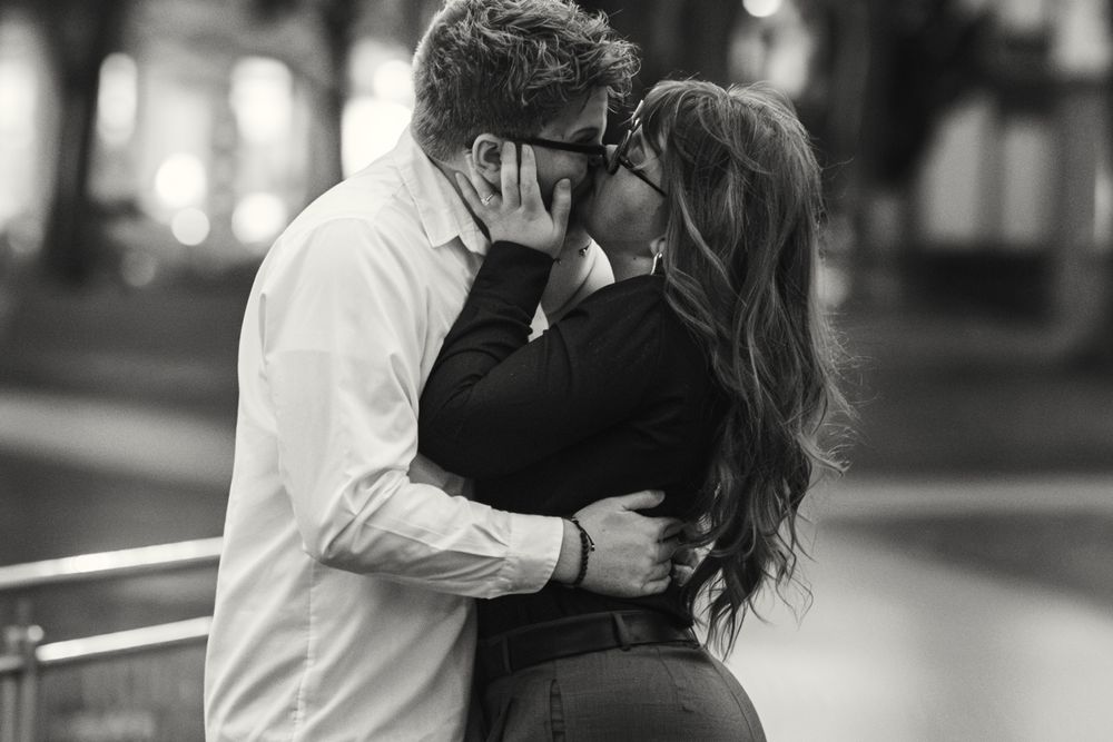 A romantic black and white photo shows a couple in an intimate embrace as they share a tender moment outdoors.