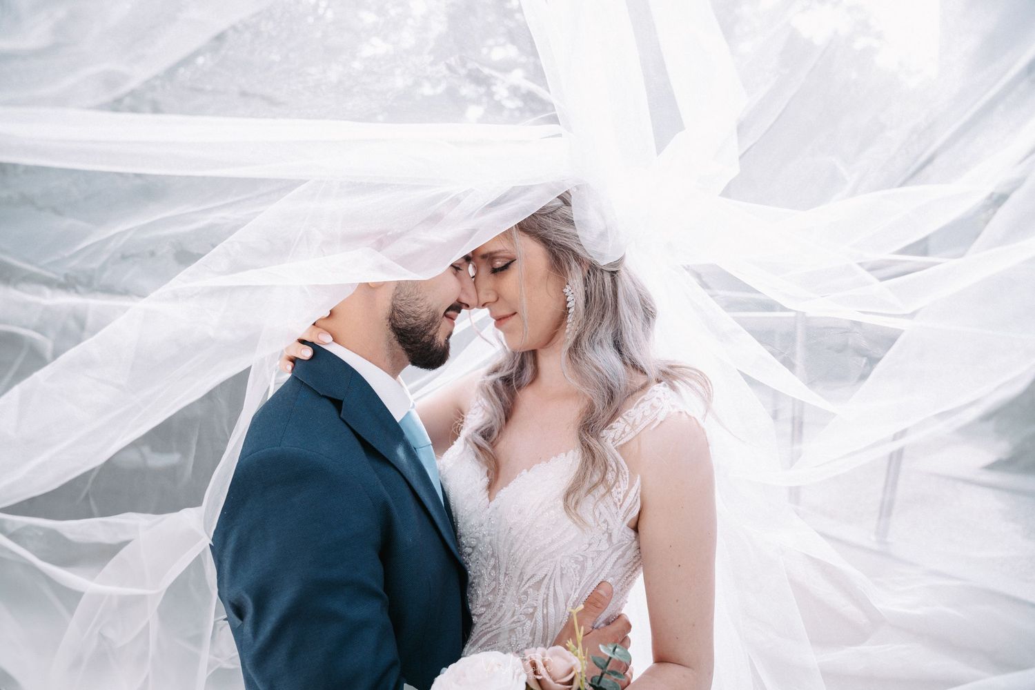 Ethereal wedding portraits with flowing white veil creating dramatic effect.