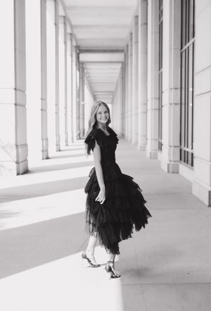 Artistic black and white photos of a flowing black dress in a columned hallway.