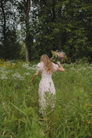 Back view of pink floral dress in wildflower meadow with forest backdrop.