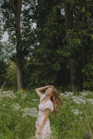 Dreamy summer scene with flowing dress in wild grass field.
