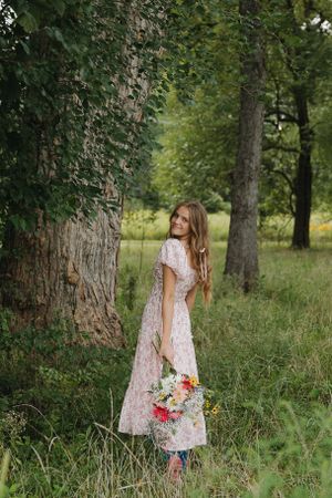 Romantic portrait against large tree trunk holding colorful bouquet.