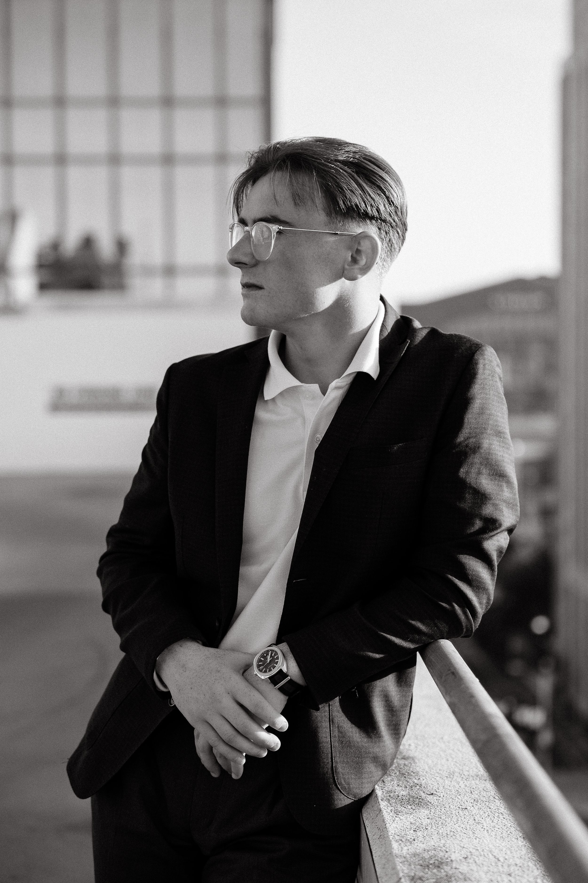 Black and white portrait of someone in formal wear against urban architecture.
