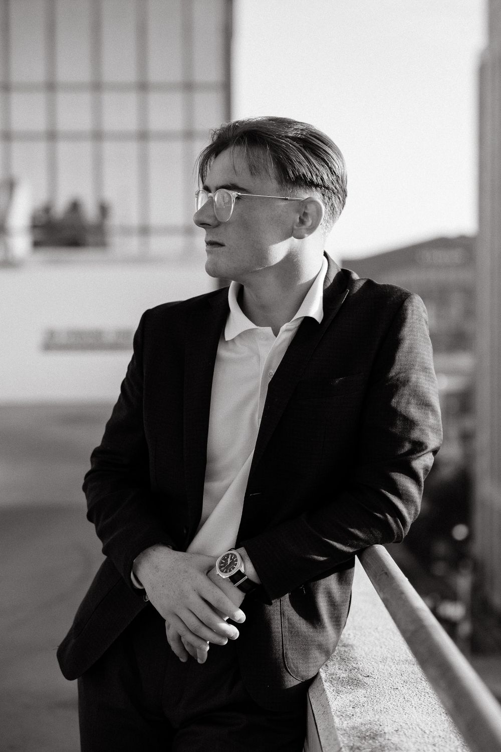 Black and white portrait of someone in formal wear against urban architecture.