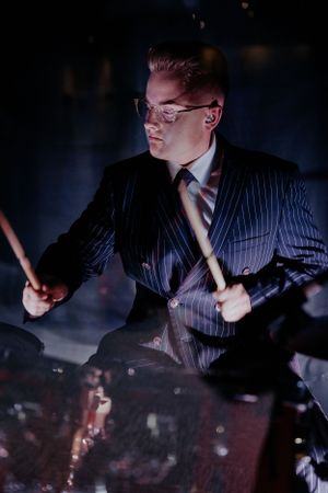 Dramatic low-light shots of a drummer performing in a pinstripe suit.