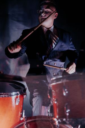 Close-up action shots of drumsticks hitting orange drums in dark lighting.