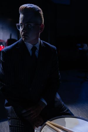 Moody silhouette of a drummer performing in dramatic stage lighting.