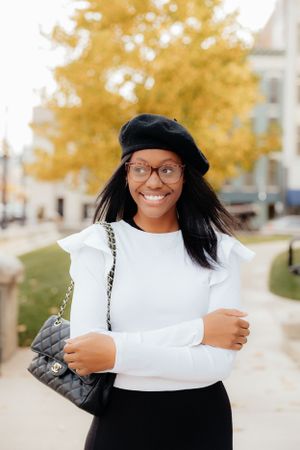 Autumn street style featuring a white top, black beret and designer bag.