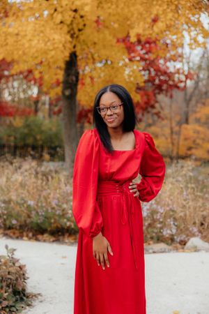Fashion portraits in a vibrant red dress against golden autumn foliage.