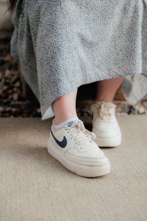 Close-up shots of white Nike sneakers paired with a grey dress.