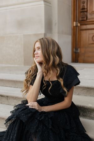 Dreamy portrait series on stone steps featuring black dress and architectural details.