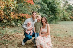 A happy family enjoying a candid outdoor photo session in a park during autumn with warm golden light.