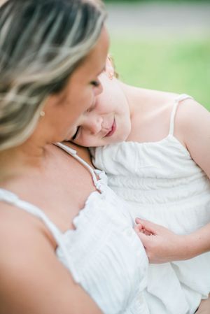 Tender close-up moment in white summer outfits against blurred background.