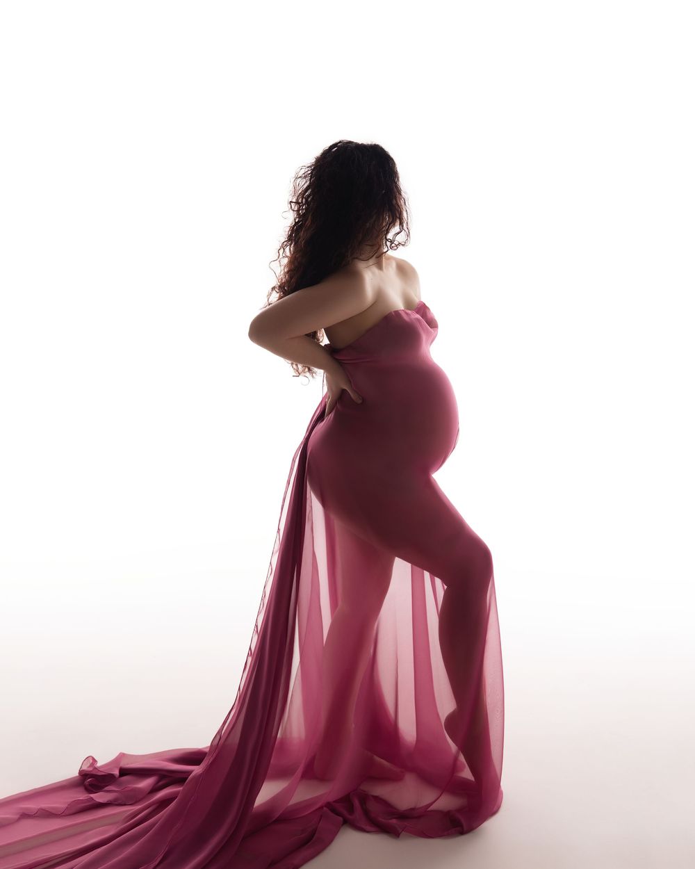 A series of maternity silhouettes in burgundy fabric show a woman's profile progressing through stages of pregnancy.