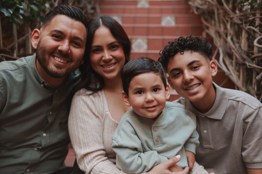 Happy family of four smiling together in casual portrait on brick staircase.