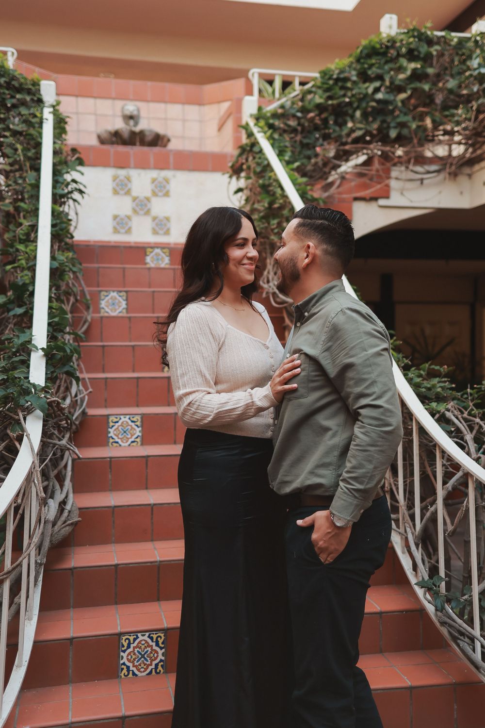 Couple sharing romantic moment on terracotta steps with decorative railings.