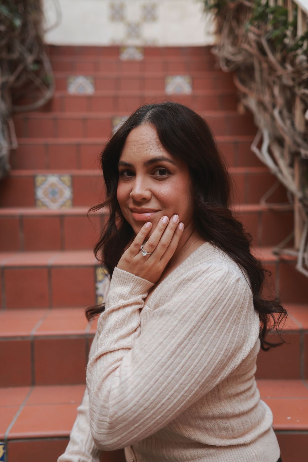 Person in cream sweater poses on terracotta stairs with decorative tile accents.