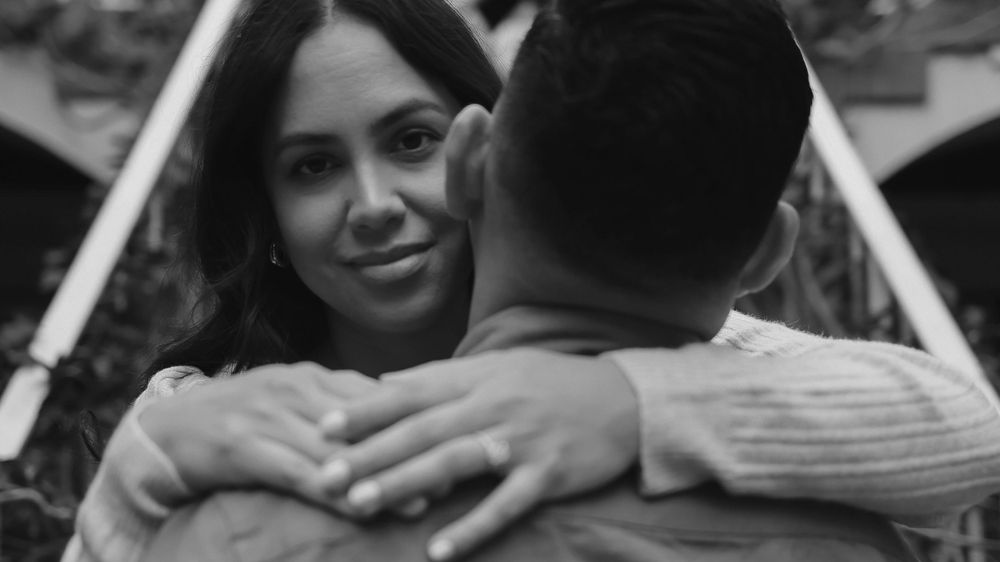 A close-up black and white photo capturing an intimate embrace between a couple on stairs.