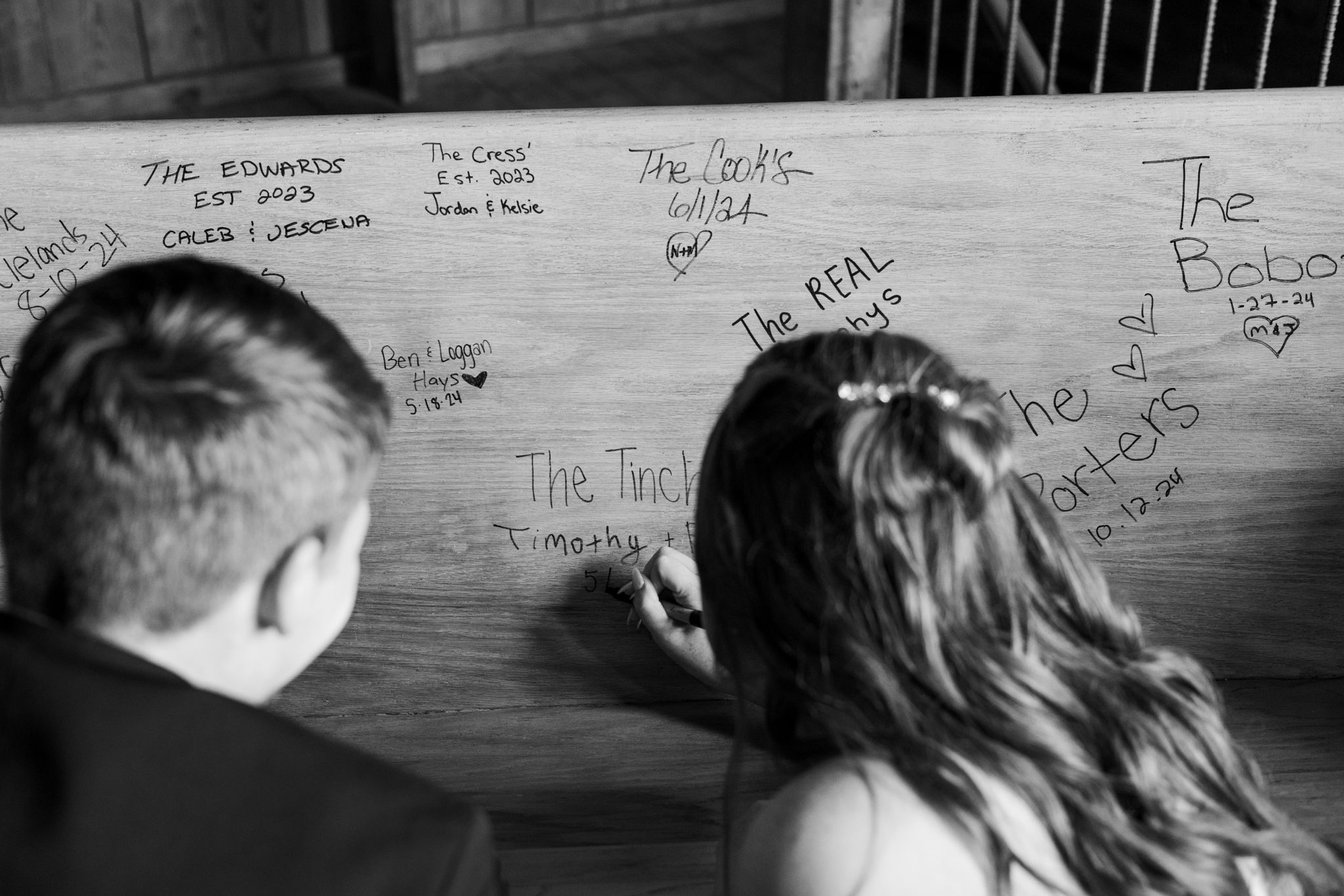 Black and white photographs of handwritten names and messages on a wooden wall or surface.