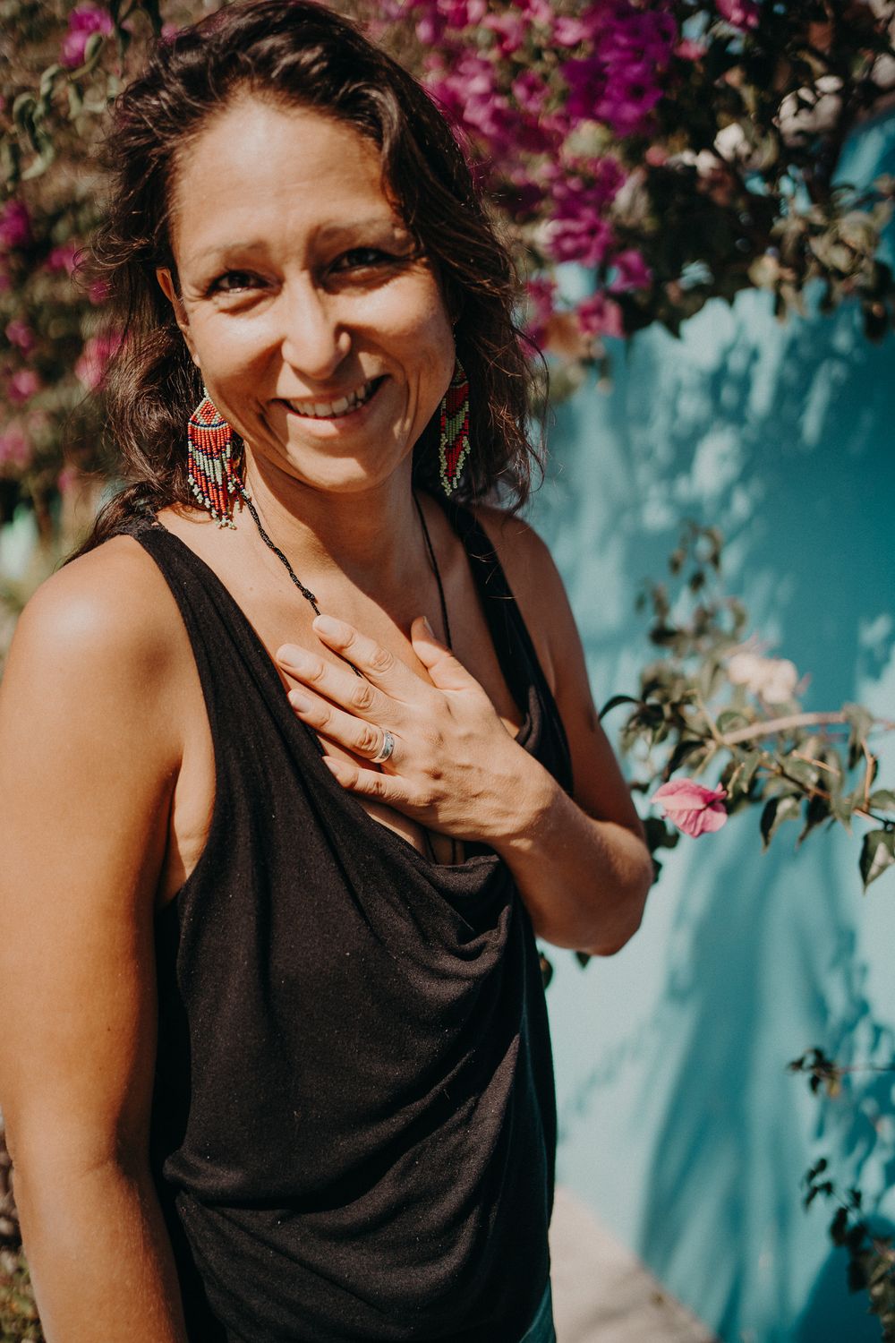 Colorful flowers bloom against a turquoise wall in a tropical outdoor setting photoshoot in Puerto Morelos.