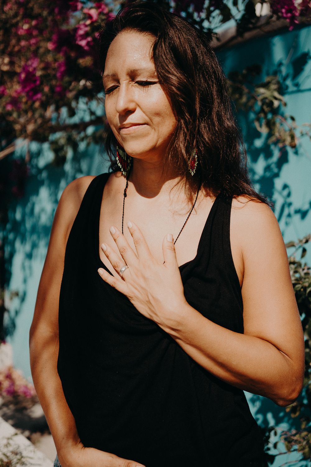 Artistic portrait against a turquoise wall with pink bougainvillea flowers in the background photoshoot in Puerto Morelos.