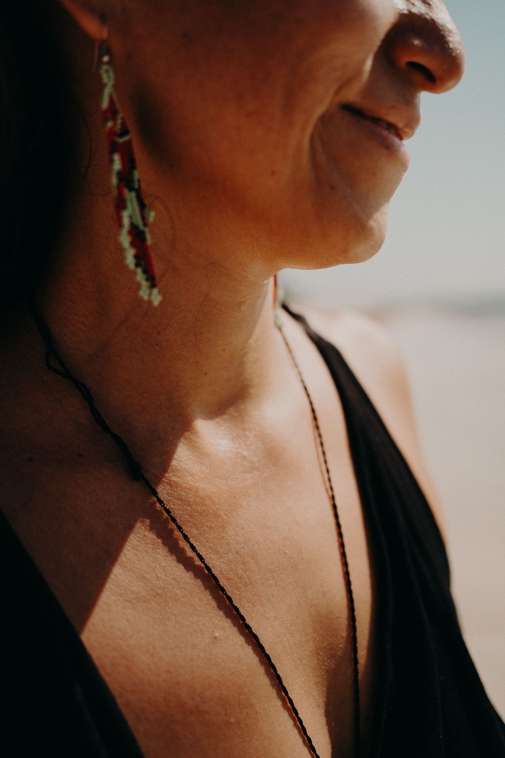 Close-up shot of decorative dangling earrings and a black tank top strap against sun-kissed skin photoshoot in Puerto Morelos.