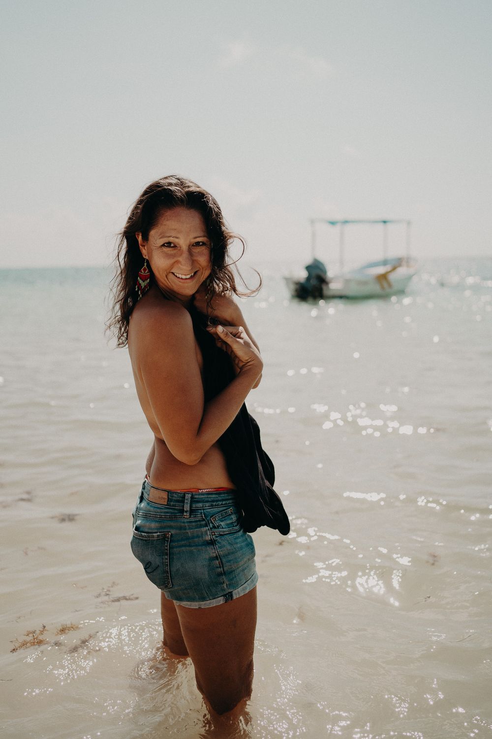 Beachside portrait with sparkling water and a small boat in the background photoshoot in Puerto Morelos.