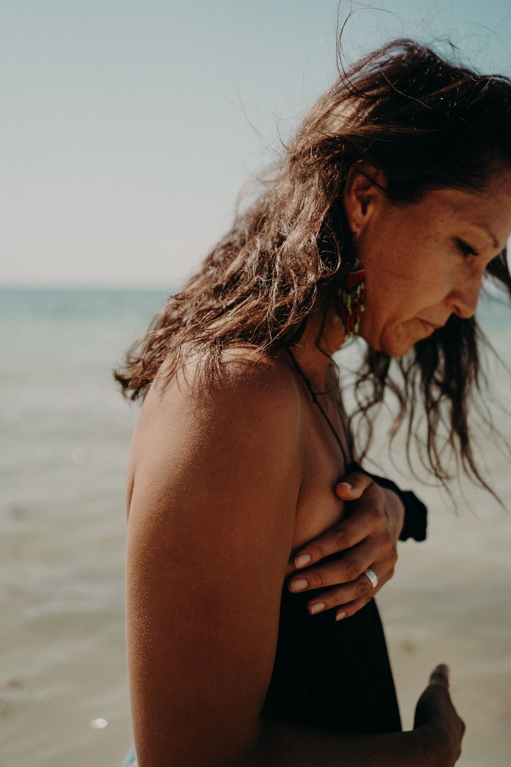 Artistic seaside portrait with wind-swept hair against a soft ocean backdrop photoshoot in Puerto Morelos.