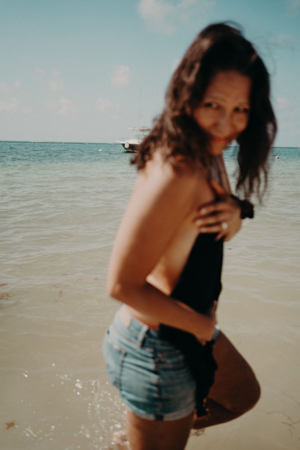 Candid beach portrait with gentle waves and clear blue sky in the background photoshoot in Puerto Morelos.