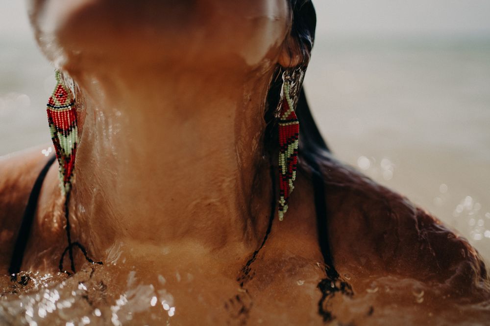 Close-up detail of ornate dangling earrings with water droplets in tropical sunlight photoshoot in Puerto Morelos.