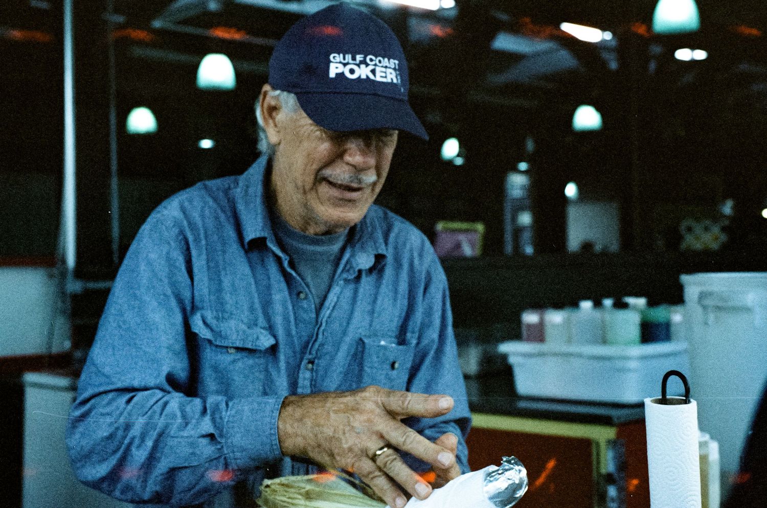 Worker in denim jacket and cap takes break at casual dining establishment.
