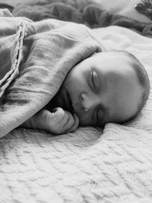 A series of black and white photos showing a peaceful sleeping baby on textured bedding.