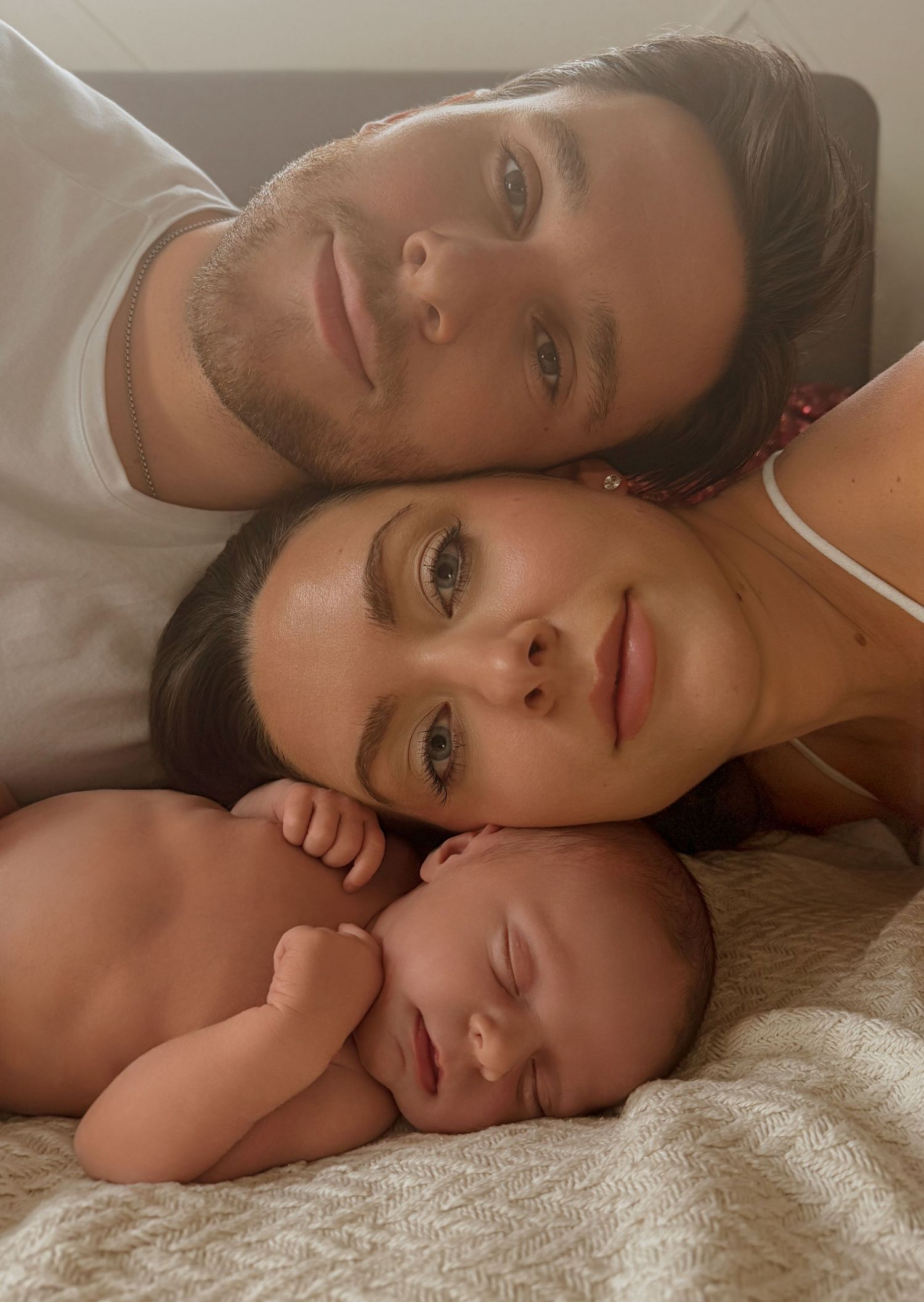 An intimate family portrait with parents lying close to their newborn baby.