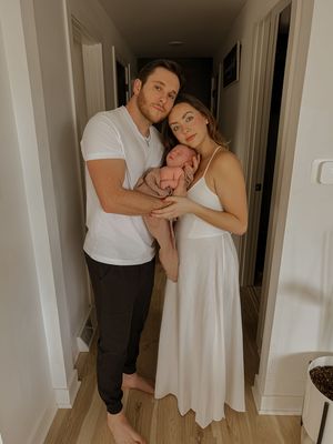 A family standing together in a hallway holding their newborn baby.