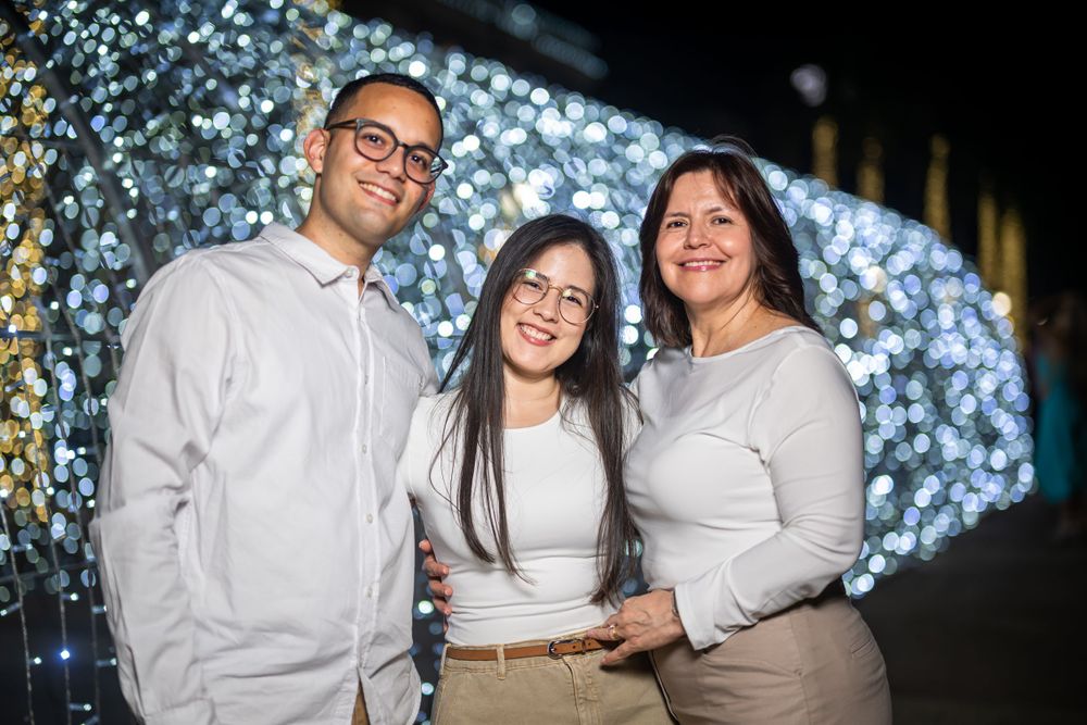 Group portrait in front of sparkling holiday lights display at night.