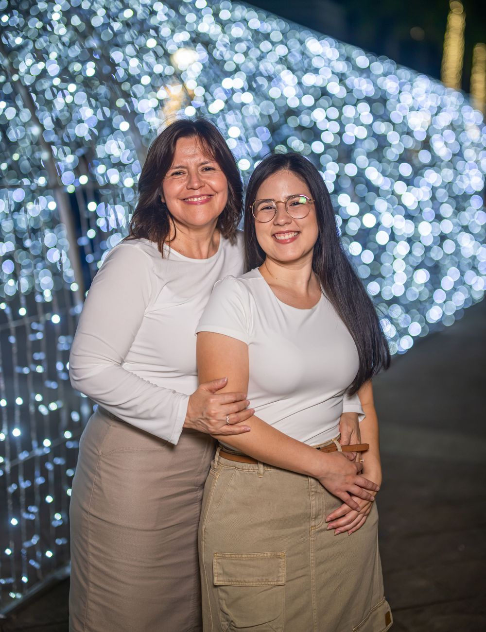 Two people posing together against a backdrop of sparkling blue lights.