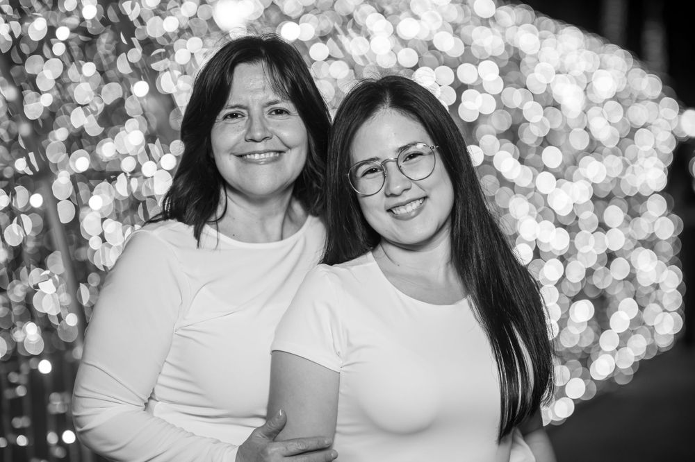 Black and white portrait of two people smiling with bokeh lights in background.