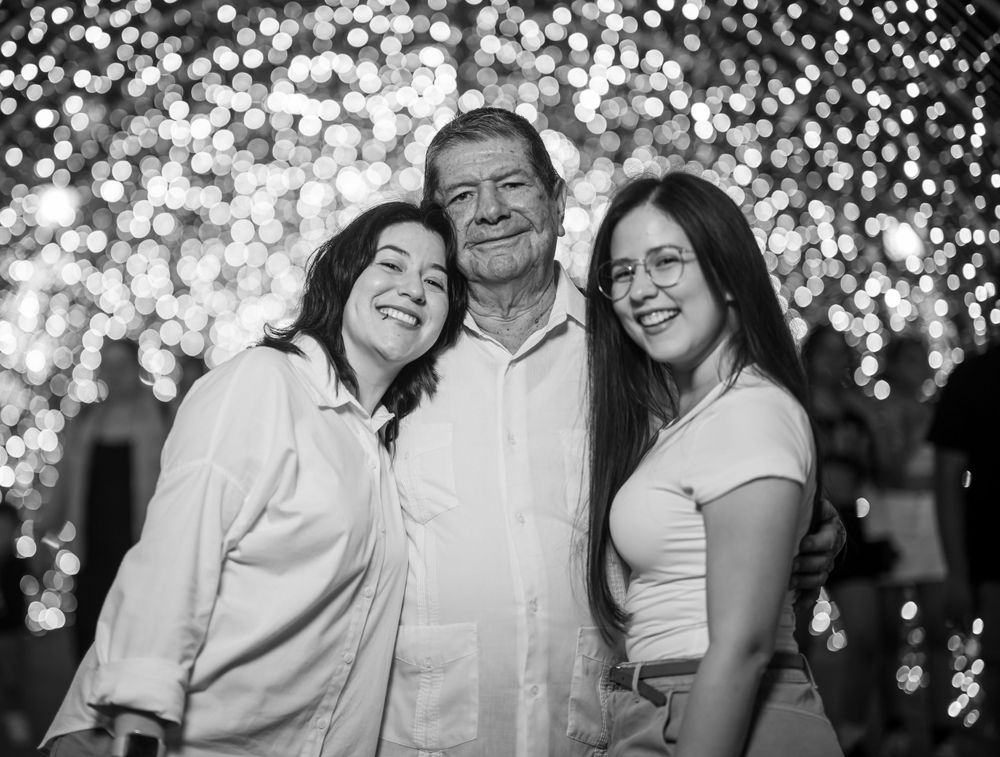 Black and white family portrait with glittering lights in background.