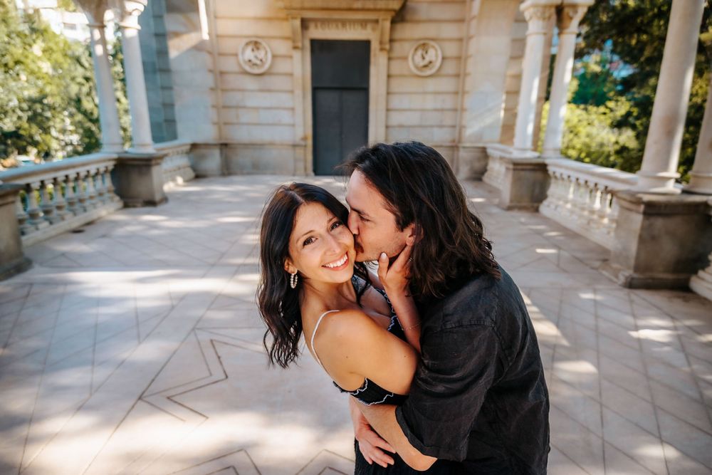 Couple smiling joyfully under the trees of Ciutadella Park.