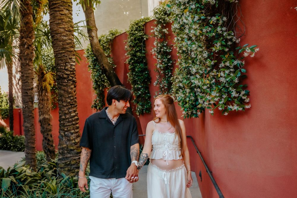 Expecting parents embracing in the colorful patio of Casa Vicens.