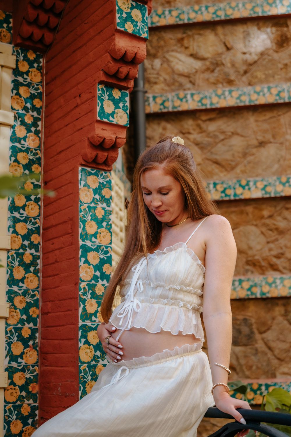 Jenna glowing with joy, holding her baby bump in Casa Vicens during her maternity session.