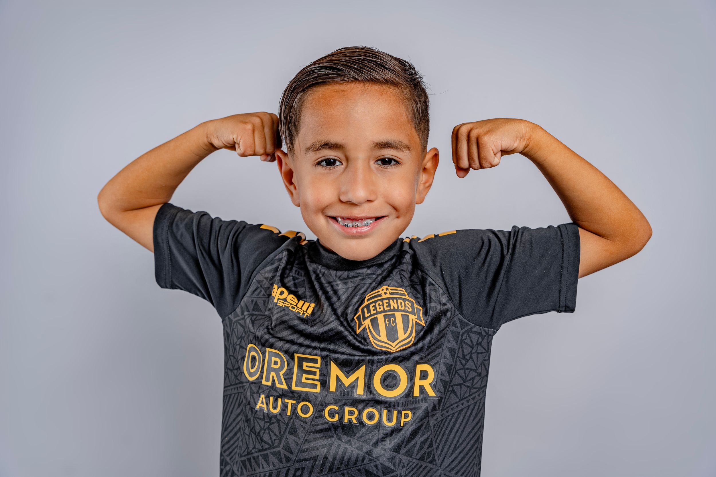 Athlete in dark Legends FC jersey shows playful expressions during photo session.