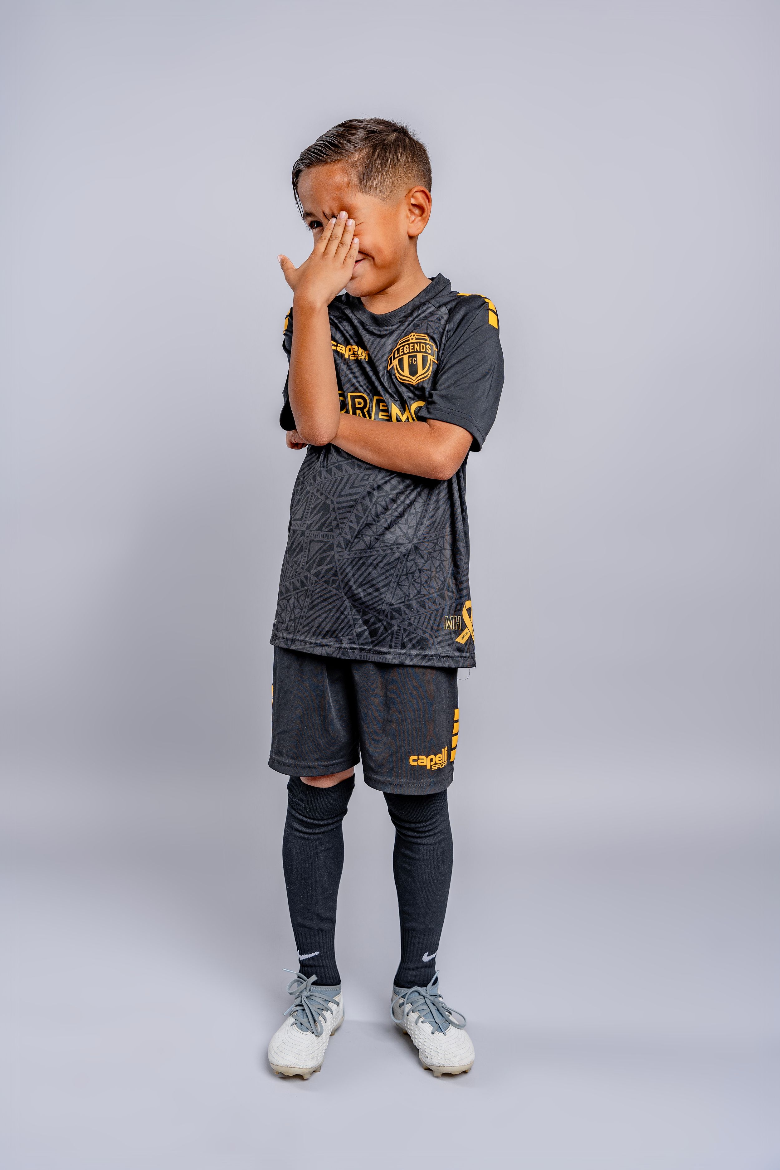 Athlete in black Legends FC uniform strikes emotional poses against grey background.