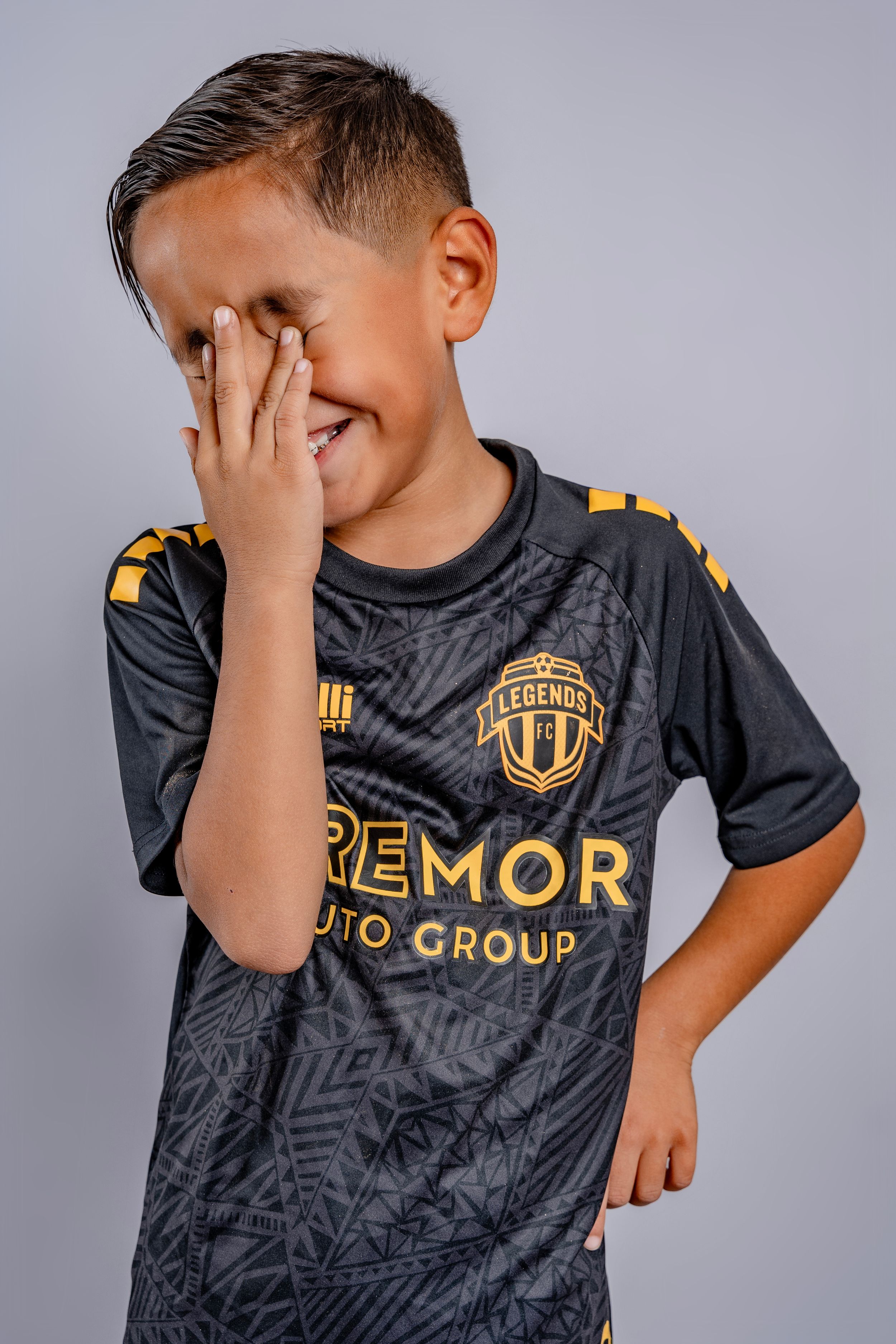 Soccer player makes playful expressions while wearing black team uniform with gold lettering.